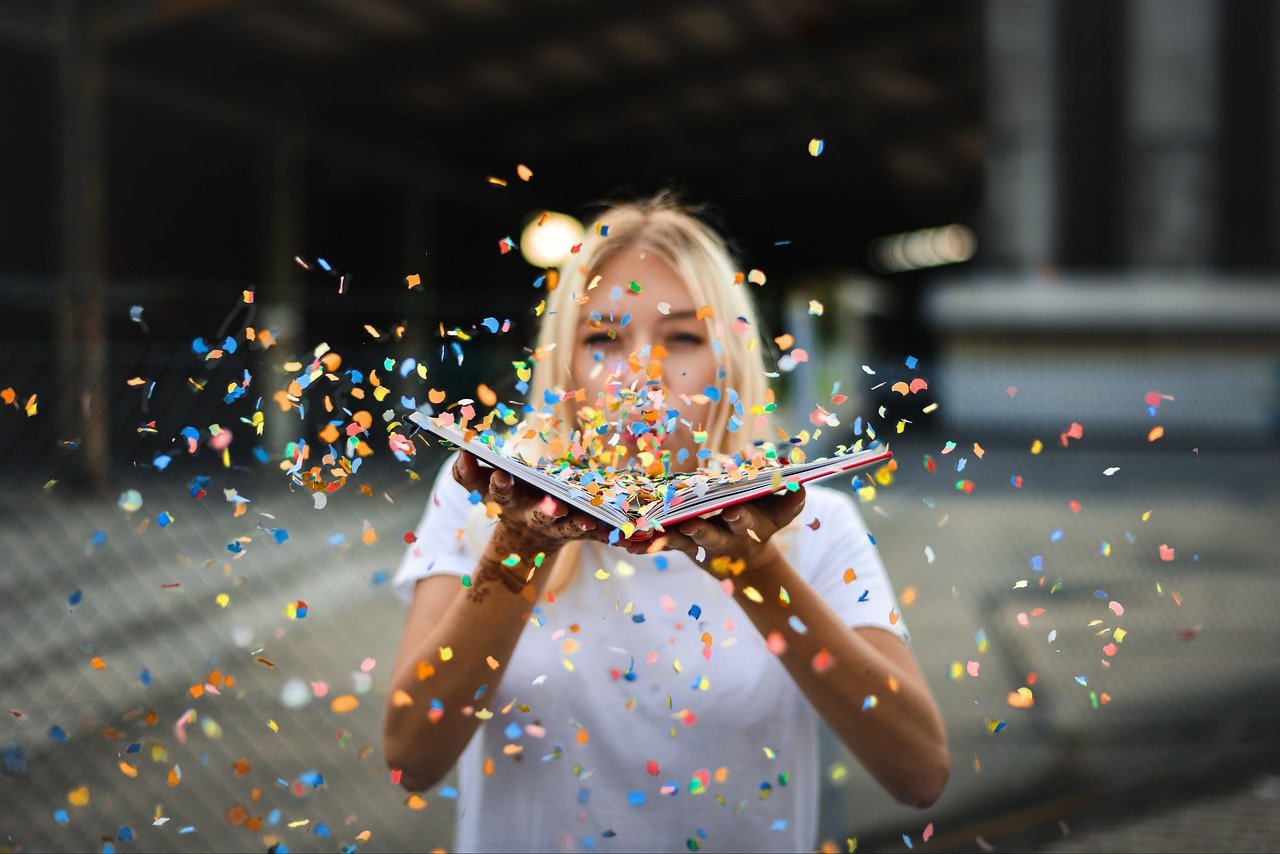 femme qui souffle sur un livre et des cotillons s'envolent